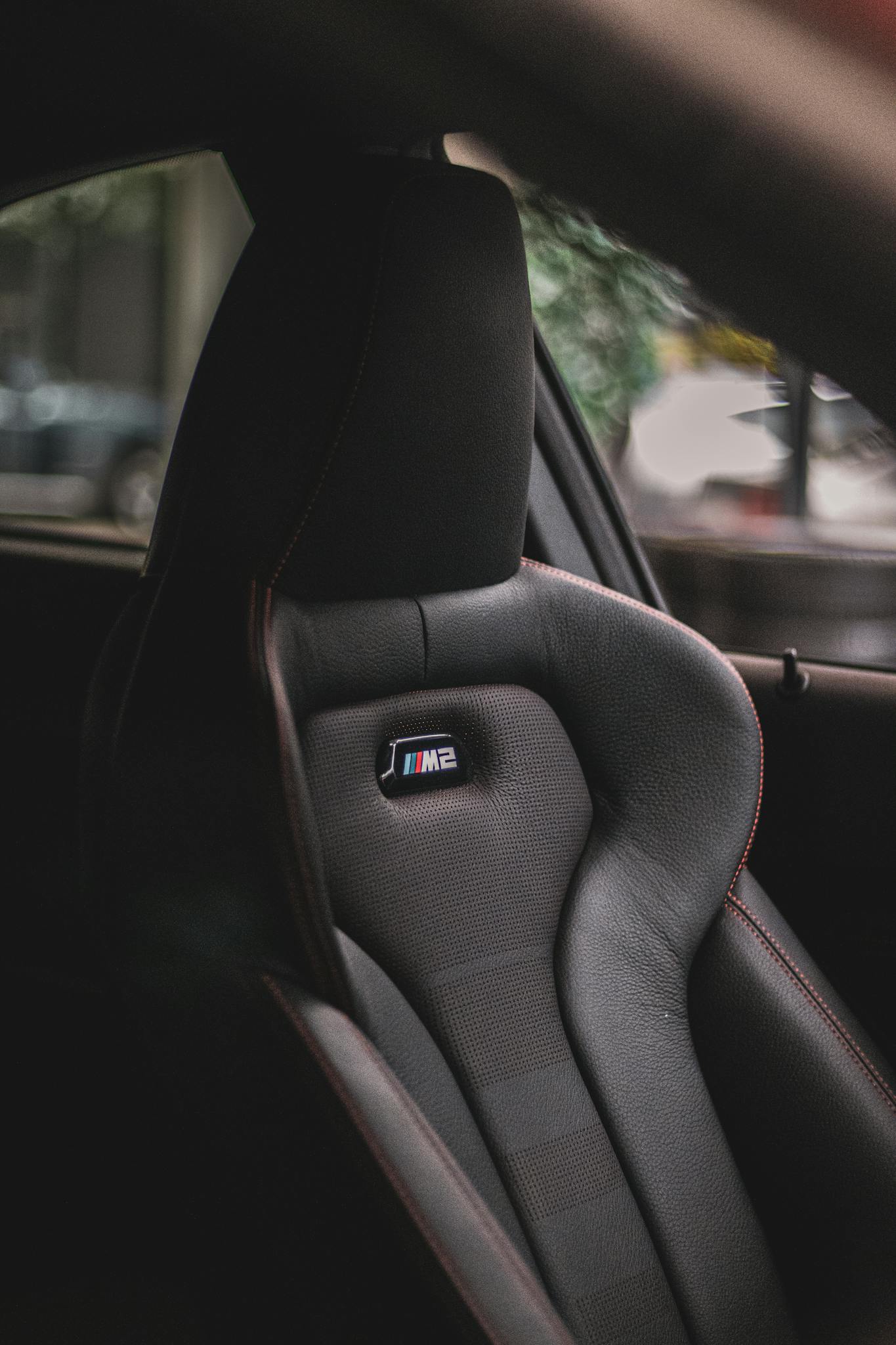 Close-up of a luxury car interior featuring a branded black leather seat with stylish design elements.