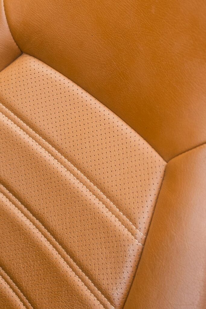 Detailed close-up of a classic car's vintage leather seat with rich texture and stitching.