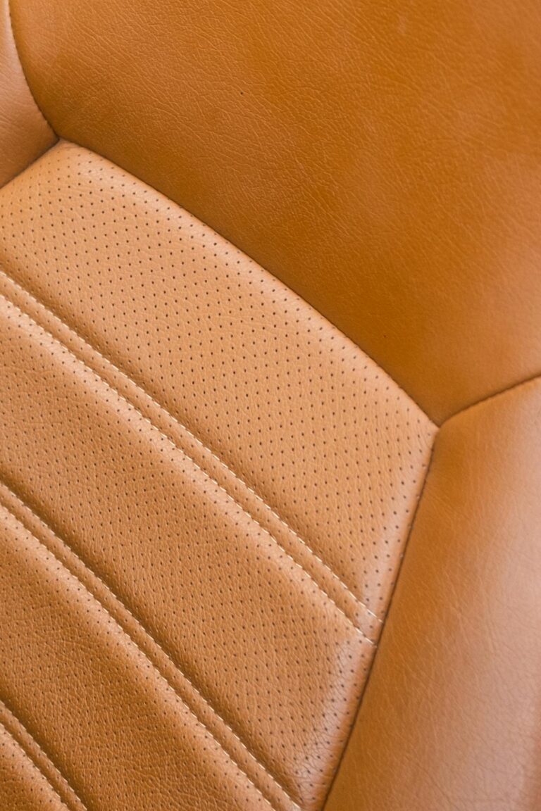 Detailed close-up of a classic car's vintage leather seat with rich texture and stitching.